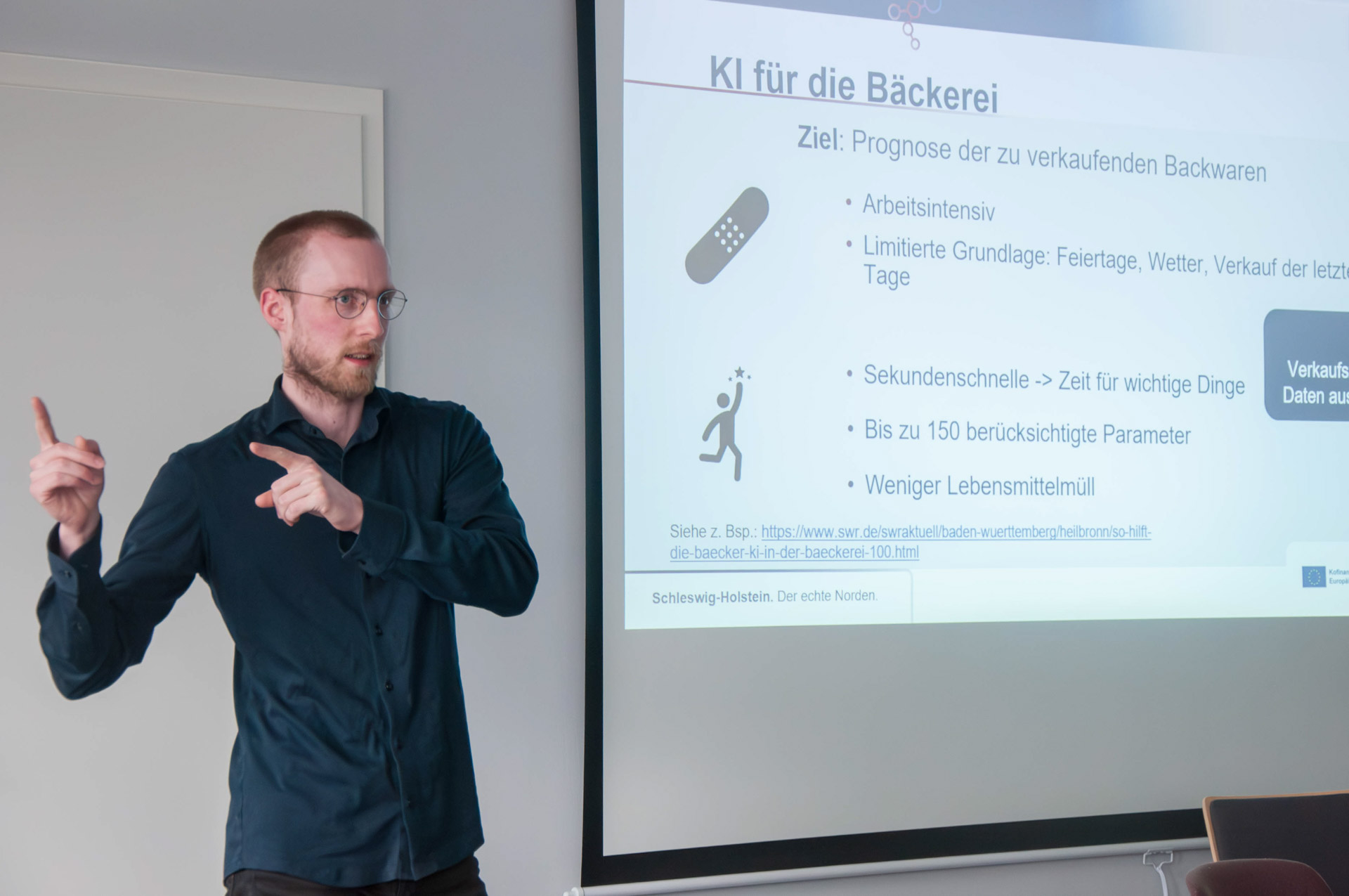 Daniel Mansfeldt hält einen Vortrag vor einer Beamerleinwand